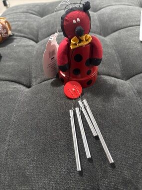 Red Ladybug Wind Chime Plush sitting on a pot colored red with black polka dots